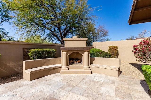 view of patio / terrace with fence and an outdoor fireplace