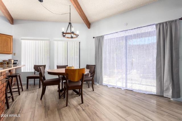 dining room with a chandelier, light hardwood / wood-style flooring, a textured ceiling, and lofted ceiling with beams