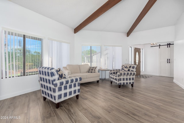 living room with a healthy amount of sunlight, vaulted ceiling with beams, a barn door, and hardwood / wood-style floors