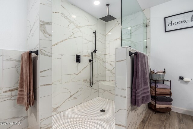 bathroom with a tile shower and wood-type flooring