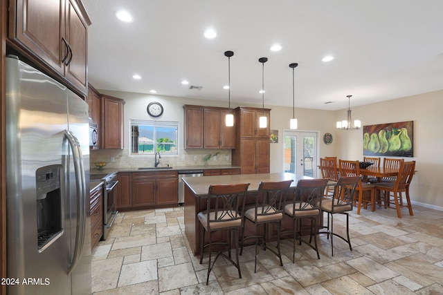 kitchen with hanging light fixtures, sink, a kitchen island, stainless steel appliances, and a breakfast bar