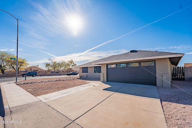 single story home with driveway, a shingled roof, an attached garage, fence, and stucco siding