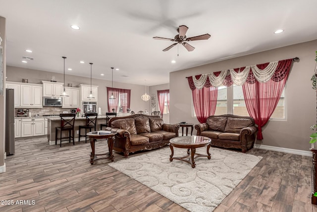 living area with a ceiling fan, recessed lighting, baseboards, and wood finished floors