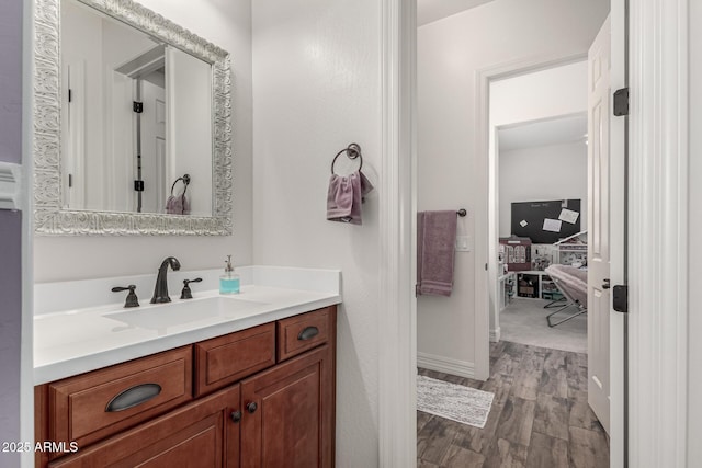 bathroom with baseboards, wood finished floors, and vanity