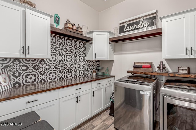 clothes washing area featuring light wood-style floors, cabinet space, and washing machine and clothes dryer