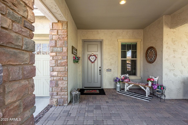 entrance to property featuring stone siding and stucco siding