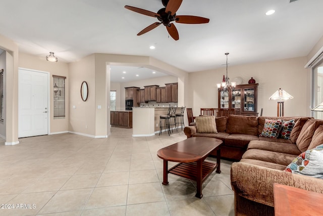 living room with ceiling fan with notable chandelier and light tile patterned floors