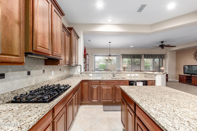 kitchen featuring ceiling fan with notable chandelier, decorative backsplash, hanging light fixtures, light stone countertops, and black appliances