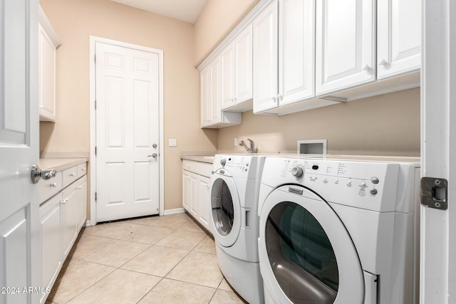 clothes washing area featuring washing machine and dryer, cabinets, light tile patterned floors, and sink