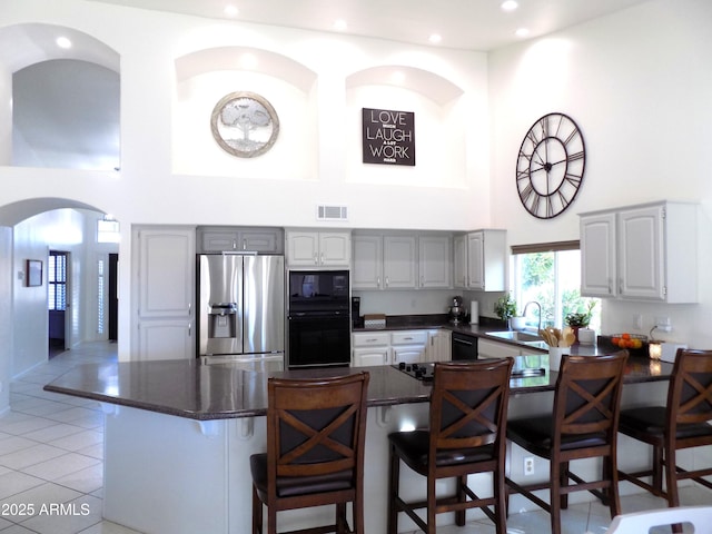 kitchen with black appliances, gray cabinets, and a kitchen breakfast bar