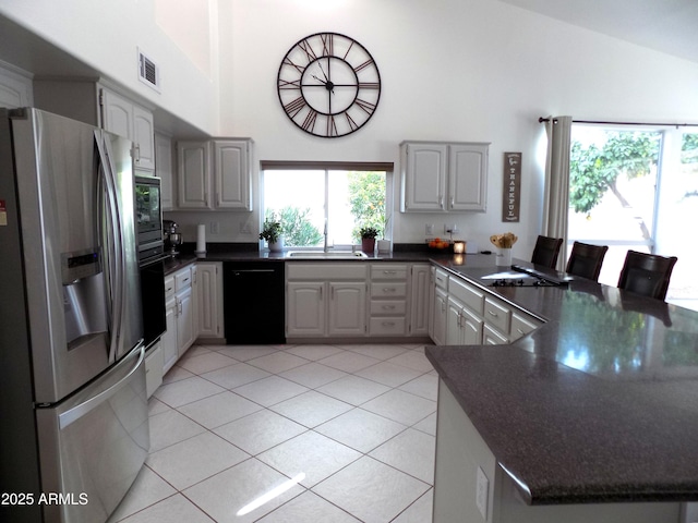 kitchen with dark countertops, dishwasher, stainless steel refrigerator with ice dispenser, and a sink