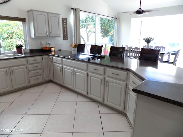 kitchen featuring dark countertops, light tile patterned floors, a sink, and black electric cooktop