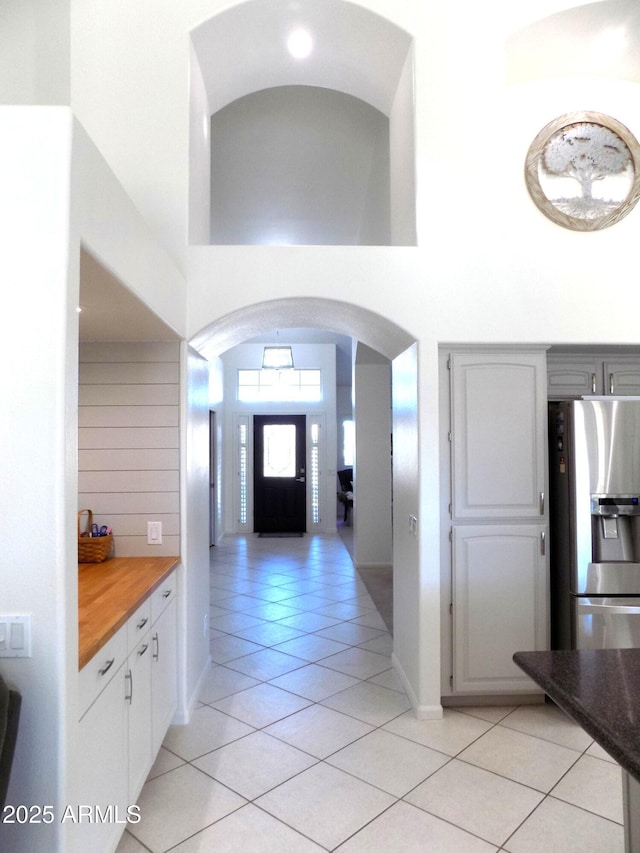 entrance foyer with light tile patterned floors, a high ceiling, arched walkways, and baseboards