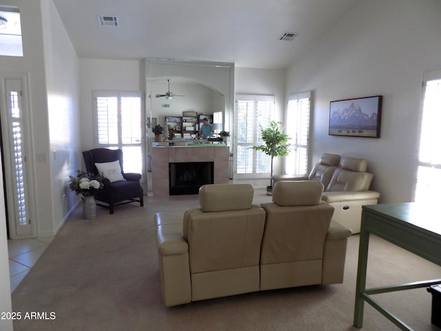 living area featuring lofted ceiling, light carpet, visible vents, and a tiled fireplace