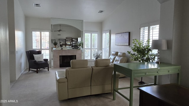 living room with light carpet, a tiled fireplace, visible vents, and a ceiling fan