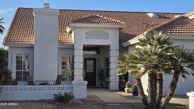 view of front facade featuring a fenced front yard, a tile roof, a chimney, and stucco siding