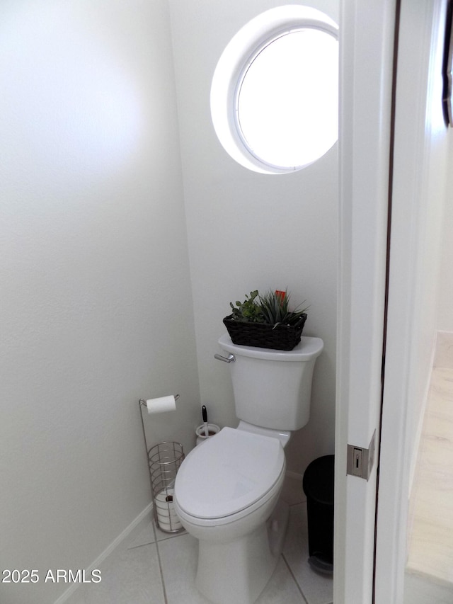 bathroom with toilet, baseboards, and tile patterned floors