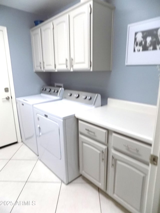 washroom featuring cabinet space, washing machine and dryer, and light tile patterned floors