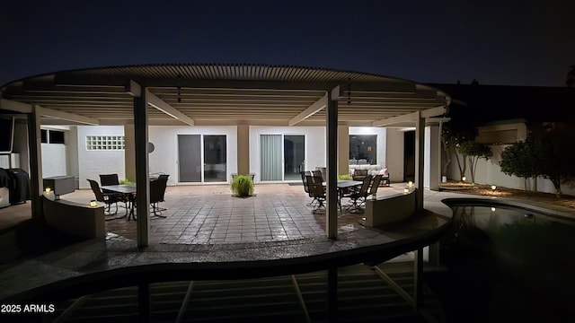 patio at night with outdoor dining area and a pergola