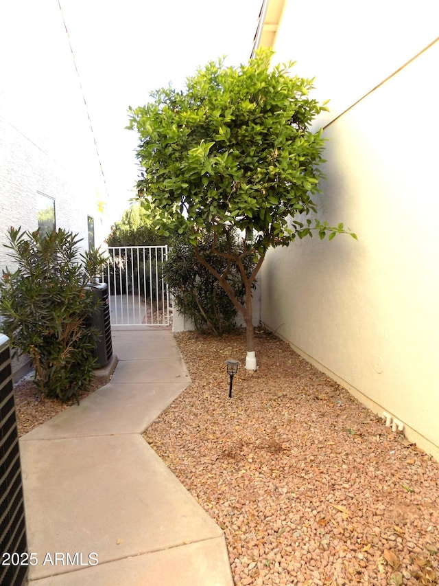 view of yard with a gate, fence, and central AC unit