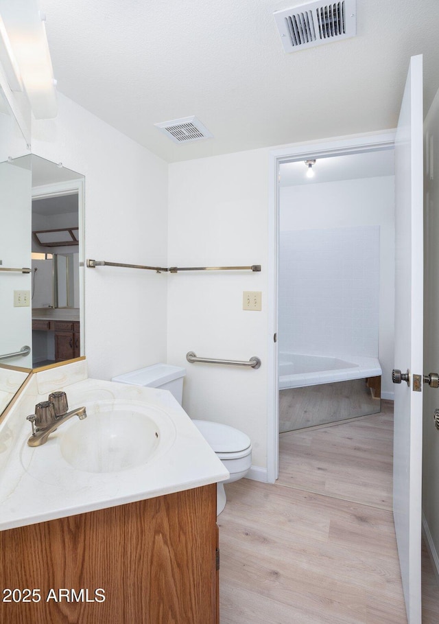 bathroom with hardwood / wood-style flooring, vanity, and toilet