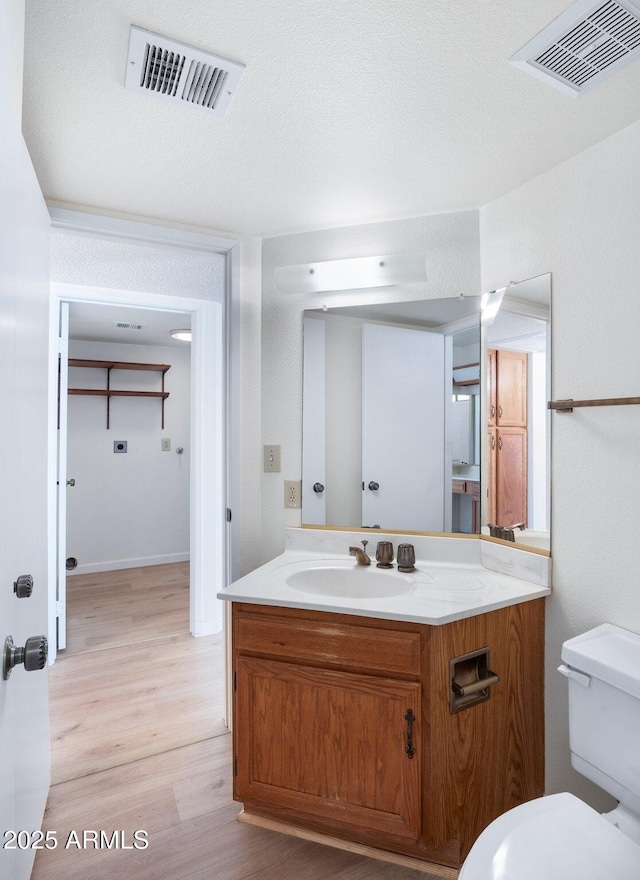 bathroom featuring vanity, a textured ceiling, wood-type flooring, and toilet