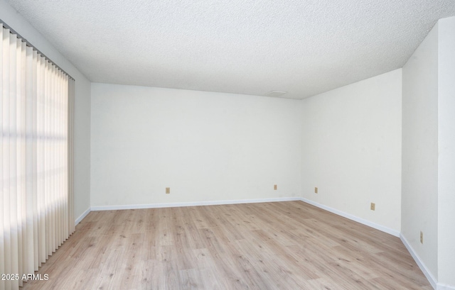 empty room with a textured ceiling and light hardwood / wood-style floors