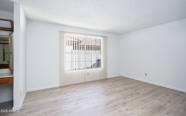 spare room with light hardwood / wood-style floors and a textured ceiling