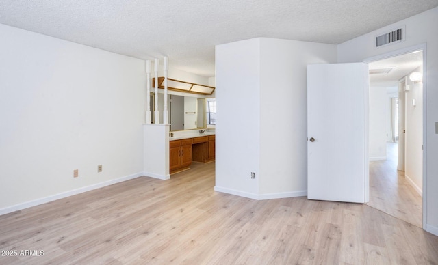 unfurnished bedroom featuring connected bathroom, a textured ceiling, and light hardwood / wood-style floors