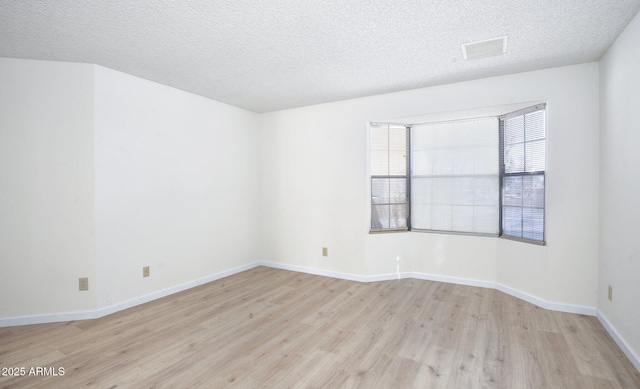 unfurnished room with light hardwood / wood-style flooring and a textured ceiling