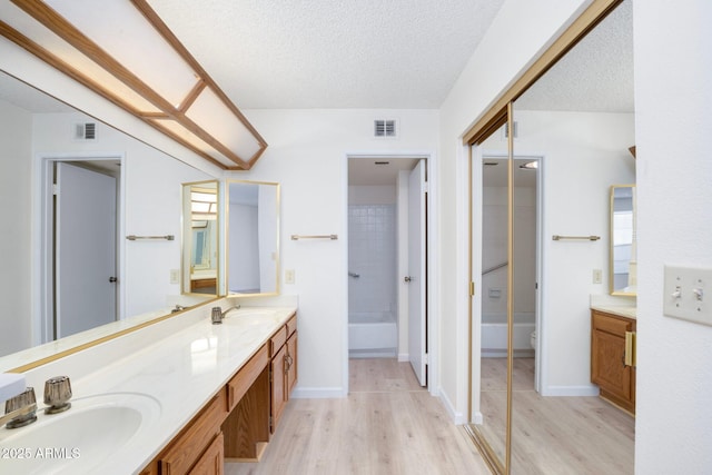 bathroom featuring wood-type flooring, vanity, a textured ceiling, and toilet