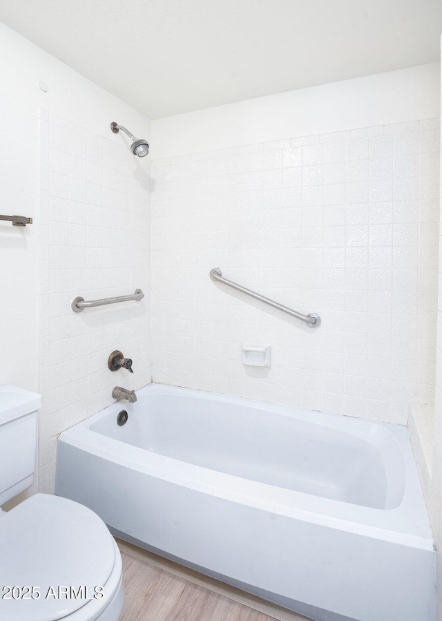 bathroom featuring tiled shower / bath combo, wood-type flooring, and toilet