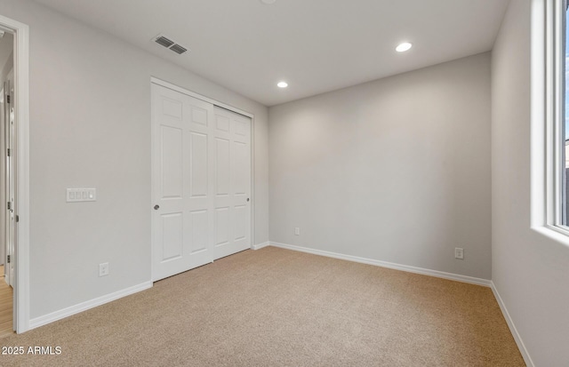 unfurnished bedroom with light carpet and a closet