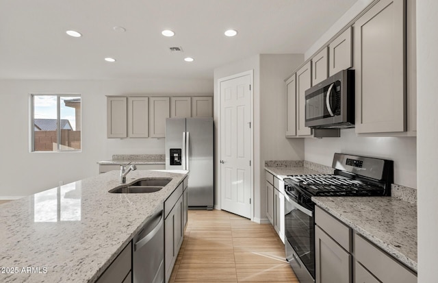 kitchen with light stone countertops, appliances with stainless steel finishes, and gray cabinetry