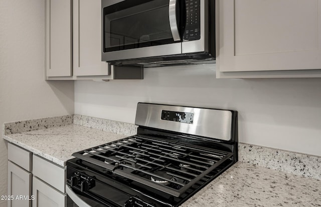 details with white cabinetry, light stone countertops, and appliances with stainless steel finishes