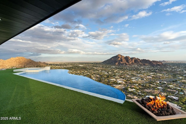 view of swimming pool featuring a mountain view, a lawn, and a jacuzzi