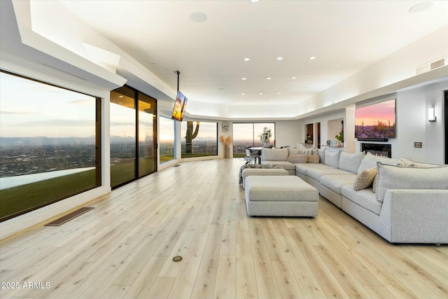 living room with recessed lighting, visible vents, a glass covered fireplace, and hardwood / wood-style flooring