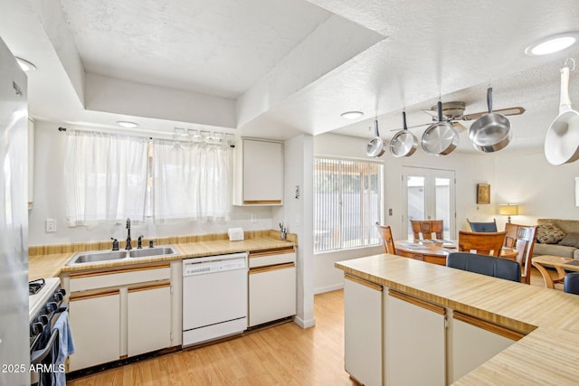 kitchen featuring sink, white cabinets, white dishwasher, gas range oven, and light hardwood / wood-style flooring