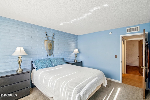 bedroom with brick wall, light carpet, and a textured ceiling