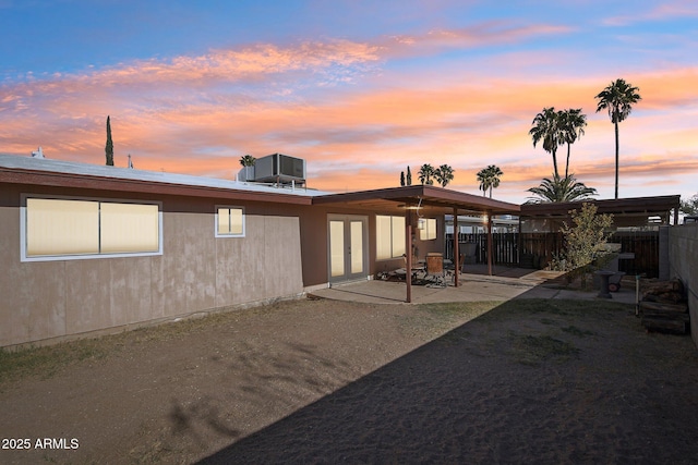 back house at dusk with a patio and central AC unit