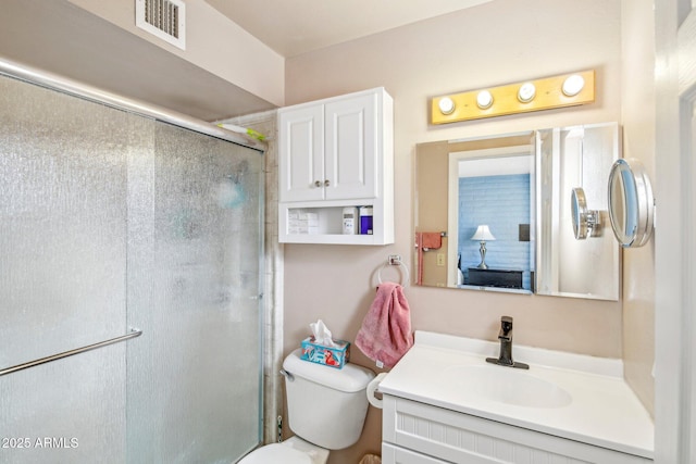 bathroom with vanity, toilet, and a shower with door