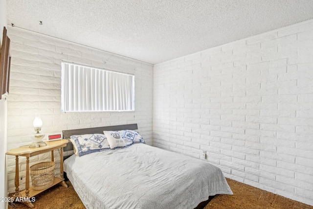 bedroom with brick wall, carpet flooring, and a textured ceiling