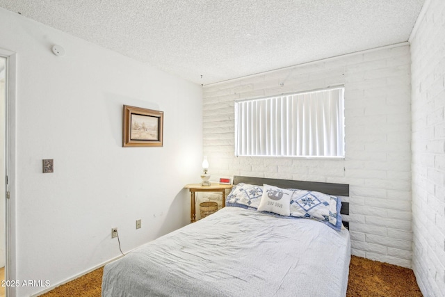 bedroom featuring a textured ceiling and brick wall