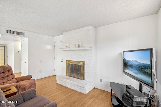 living room with a fireplace, hardwood / wood-style floors, and a textured ceiling