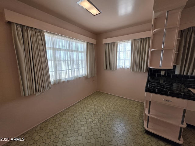 unfurnished dining area featuring baseboards and tile patterned floors