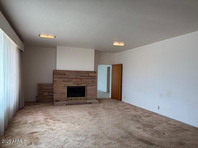 unfurnished living room with a stone fireplace and carpet floors