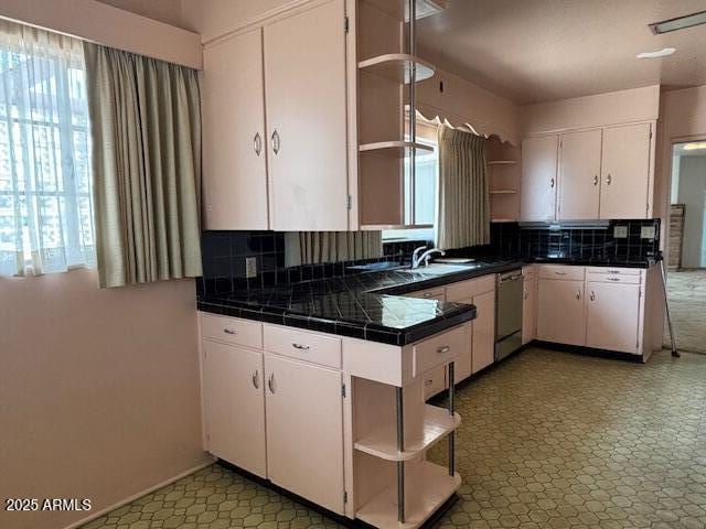 kitchen with open shelves, stainless steel dishwasher, decorative backsplash, and white cabinetry
