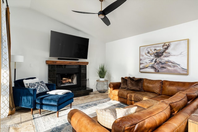 living room featuring ceiling fan, a tiled fireplace, and vaulted ceiling