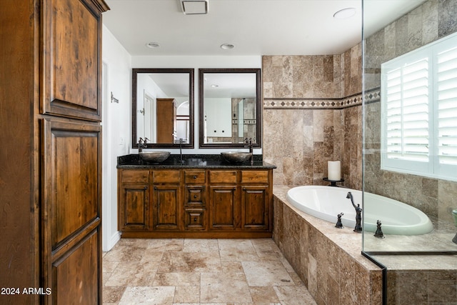 bathroom with vanity, a relaxing tiled tub, and tile walls