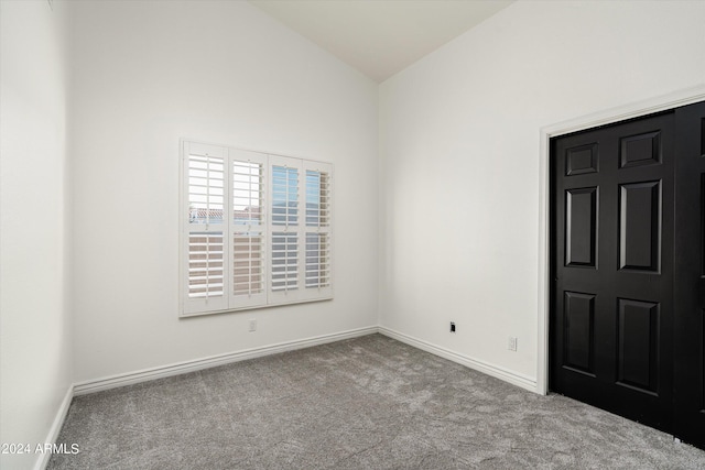 spare room with light carpet and vaulted ceiling